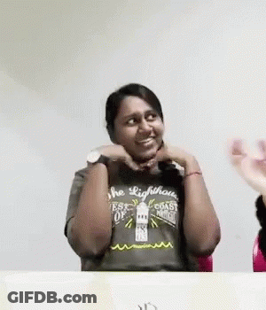 A Woman Wearing A Lighthouse T-Shirt Is Sitting At A Table With Her Hands On Her Face . GIF