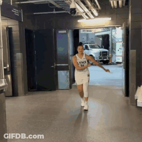 A Woman Wearing A Lynx Jersey Is Walking Down A Hallway GIF