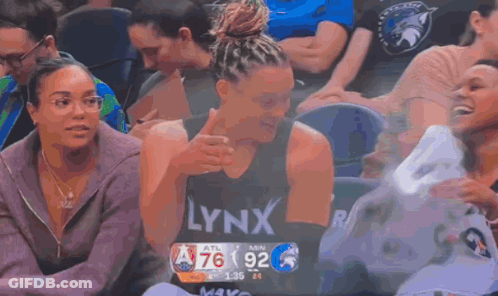 A Woman Wearing A Lynx Shirt Is Sitting In The Stands During A Basketball Game GIF