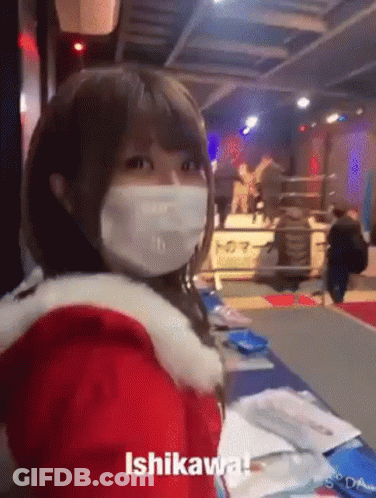 A Woman Wearing A Mask And A Santa Claus Outfit Is Standing In A Room . GIF