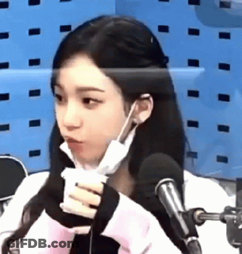 A Woman Wearing A Mask And Earphones Is Sitting In Front Of A Microphone . GIF