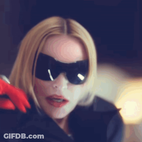 A Woman Wearing A Mask And Sunglasses Is Holding A Red Glove GIF