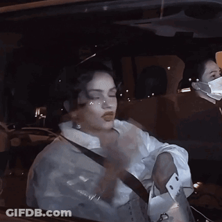 A Woman Wearing A Mask Is Driving A Car GIF