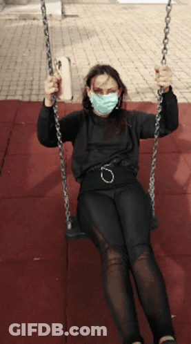 A Woman Wearing A Mask Is Swinging On A Chain GIF