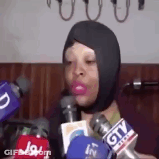 A Woman Wearing A Mask Is Talking Into Microphones . GIF