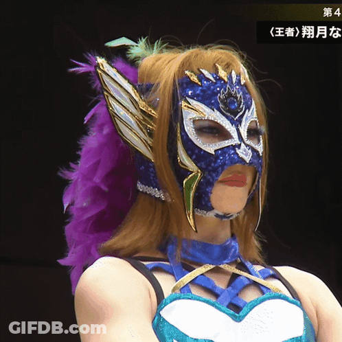 A Woman Wearing A Mask With A Purple Feather In Her Hair GIF