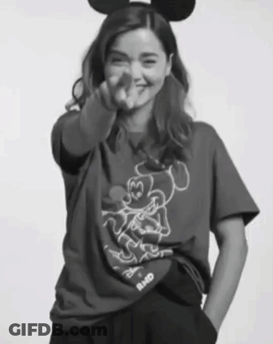 A Woman Wearing A Mickey Mouse T-Shirt Is Pointing GIF