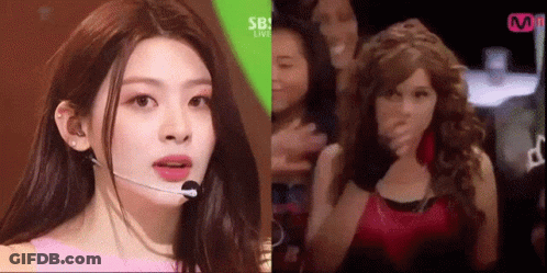 A Woman Wearing A Microphone And A Wig Is Standing Next To A Woman Wearing A Wig . GIF