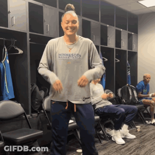 A Woman Wearing A Minnesota Basketball Shirt Is Dancing In A Locker Room GIF
