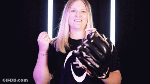 A Woman Wearing A Mizuno Glove Holds Her Fist Up GIF