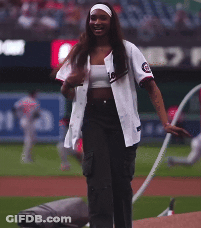 A Woman Wearing A Nationals Jersey Stands On The Field GIF