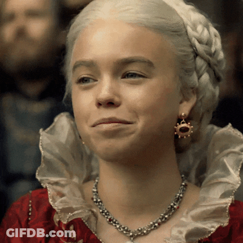 A Woman Wearing A Necklace And Earrings Is Smiling For The Camera GIF