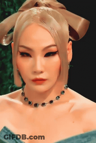 A Woman Wearing A Necklace And Earrings Looks At The Camera GIF