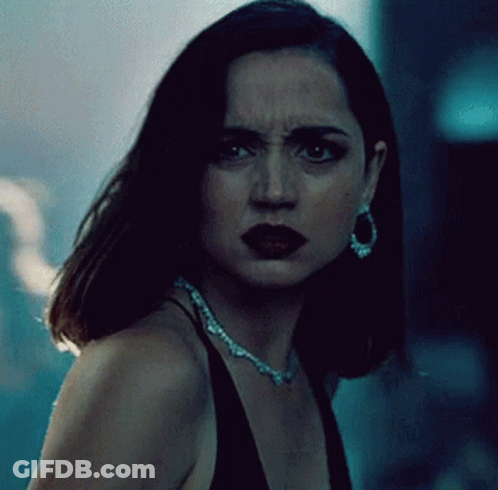 A Woman Wearing A Necklace And Earrings Looks At The Camera With A Serious Look On Her Face GIF