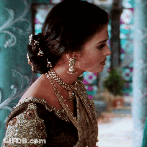 A Woman Wearing A Necklace And Earrings With A Bun GIF