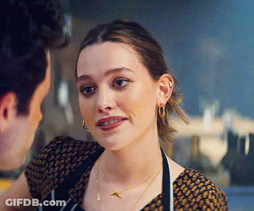 A Woman Wearing A Necklace And Hoop Earrings Is Looking At A Man . GIF