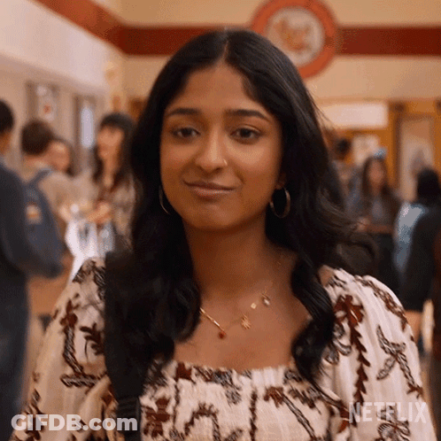 A Woman Wearing A Necklace And Hoop Earrings Is Standing In A Crowded Hallway . GIF