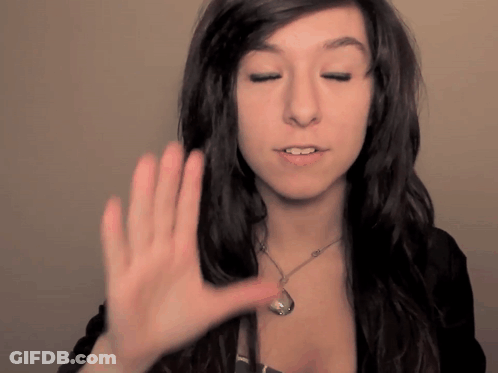 A Woman Wearing A Necklace Holds Her Hand Up To Her Face GIF