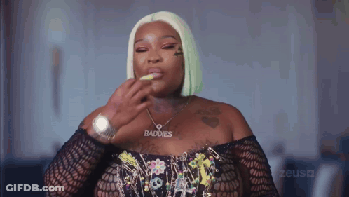 A Woman Wearing A Necklace That Says Baddies GIF