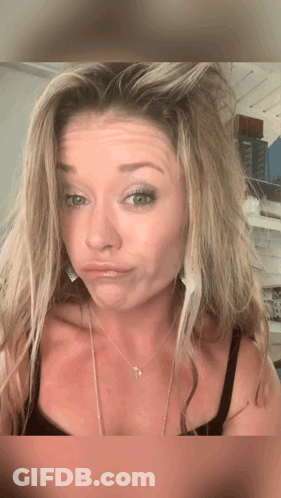 A Woman Wearing A Necklace With A Cross On It GIF