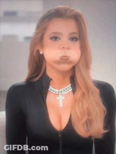A Woman Wearing A Necklace With A Cross On It Makes A Funny Face GIF