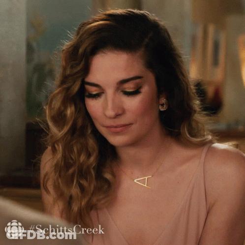 A Woman Wearing A Necklace With A Letter T On It GIF