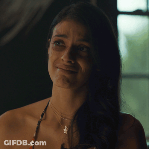 A Woman Wearing A Necklace With A Pendant That Says S On It GIF