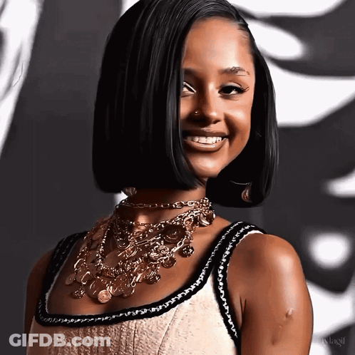 A Woman Wearing A Necklace With Coins On It Smiles For The Camera GIF
