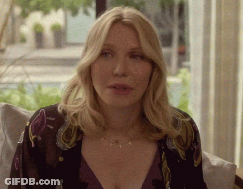 A Woman Wearing A Necklace With The Letters T And Y On It GIF