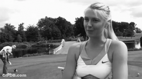 A Woman Wearing A Nike Tank Top Is Standing In A Park GIF