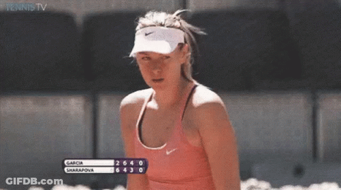 A Woman Wearing A Nike Visor And A Pink Tank Top Is Watching A Tennis Match Between Garcia And Sharapova GIF