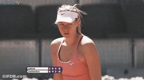 A Woman Wearing A Nike Visor And A Pink Tank Top Is Watching A Tennis Match Between Garcia And Sharapova GIF