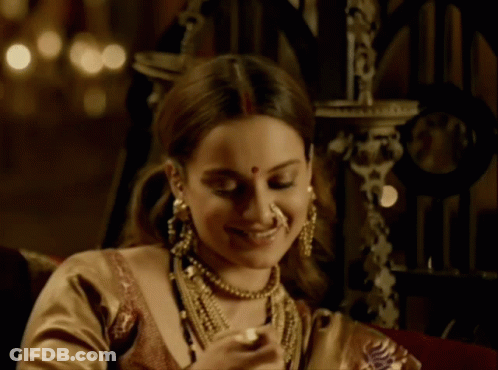 A Woman Wearing A Nose Ring And A Necklace Smiles GIF
