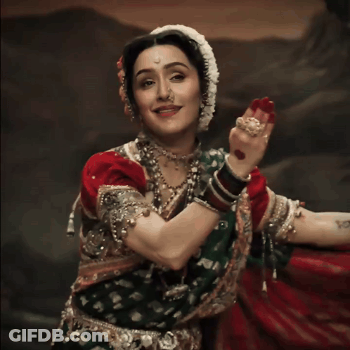 A Woman Wearing A Nose Ring And A Red And Green Dress GIF