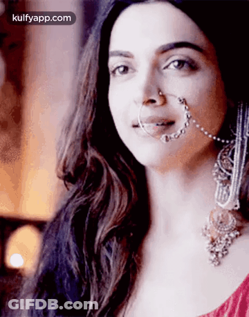 A Woman Wearing A Nose Ring And Earrings Is Looking At The Camera . GIF