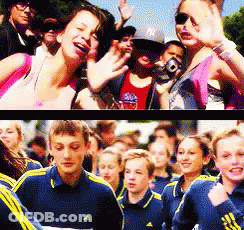 A Woman Wearing A Ny Hat Stands In Front Of A Crowd GIF