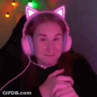 A Woman Wearing A Pair Of Pink Cat Ears Headphones Is Sitting In A Chair . GIF