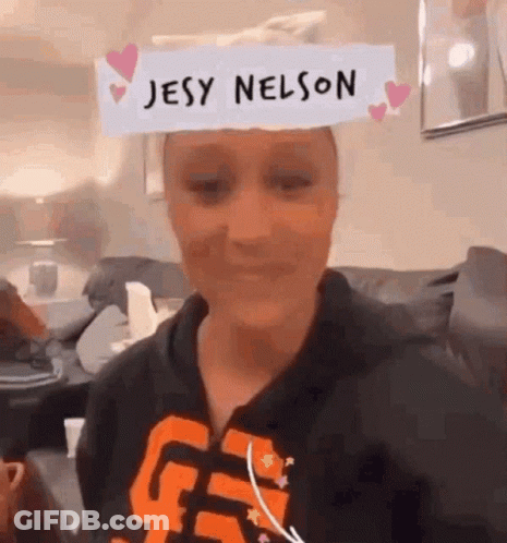 A Woman Wearing A Paper On Her Head That Says Jesy Nelson . GIF