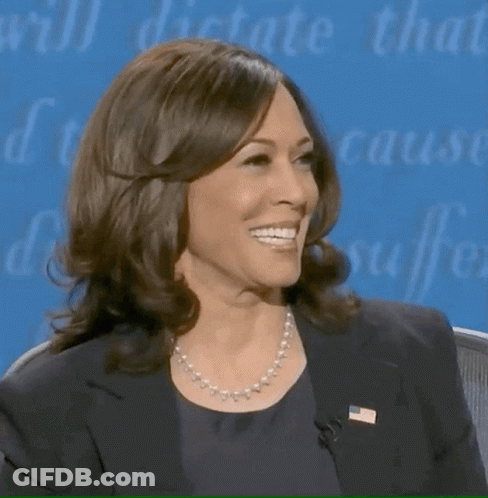 A Woman Wearing A Pearl Necklace And A Black Jacket Smiles GIF