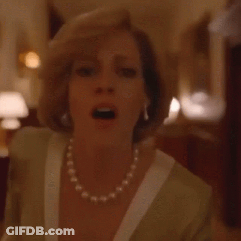 A Woman Wearing A Pearl Necklace And Gloves Is Standing On A Red Carpet In A Room . GIF