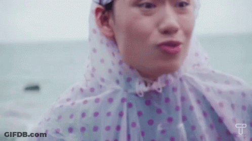 Woman In Pink And White Polka Dot Raincoat By Ocean GIF