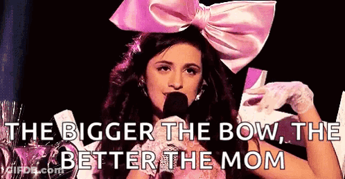 A Woman Wearing A Pink Bow And Gloves Is Talking Into A Microphone . GIF