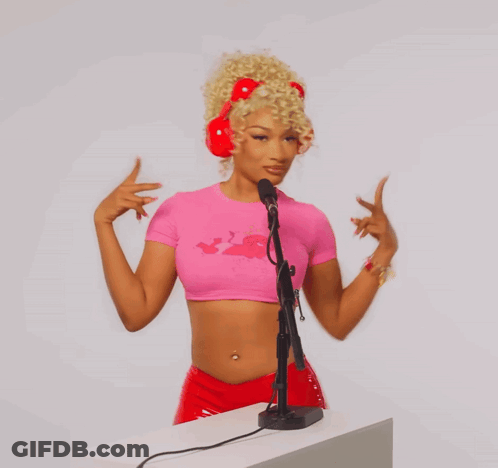 A Woman Wearing A Pink Crop Top And Red Headphones Is Standing In Front Of A Microphone GIF