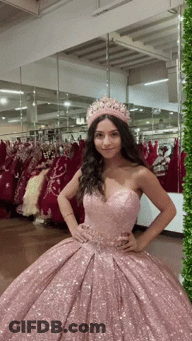 A Woman Wearing A Pink Dress And A Crown Is Standing In Front Of A Mirror GIF
