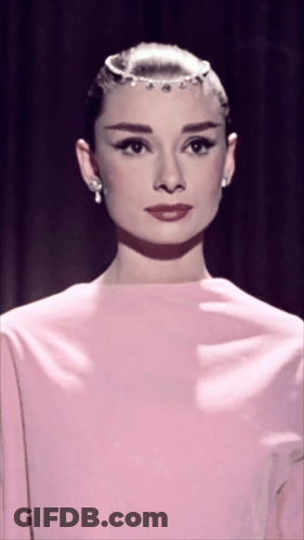 Woman In Pink Dress And Earrings Looking At Camera GIF