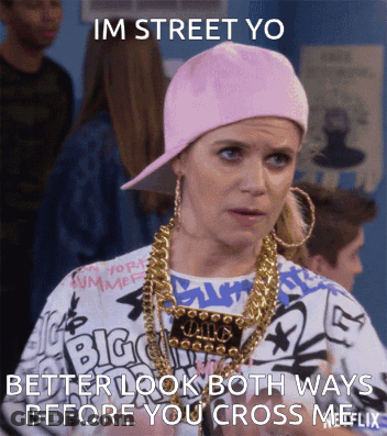A Woman Wearing A Pink Hat And Gold Chains Says " Im Street Yo Better Look Both Ways Before You Cross Me " GIF