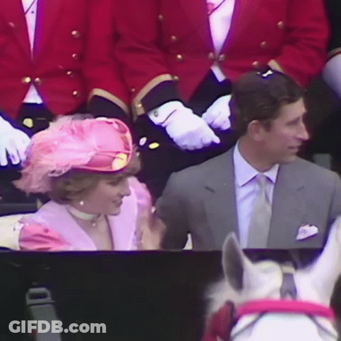 A Woman Wearing A Pink Hat Is Sitting Next To A Man In A Suit GIF