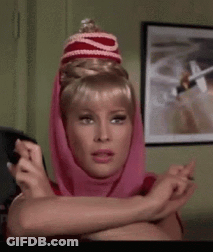 A Woman Wearing A Pink Head Scarf And A Red Hat Is Sitting In A Room . GIF