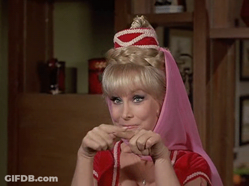 A Woman Wearing A Pink Head Scarf And A Red Top Is Making A Funny Face . GIF