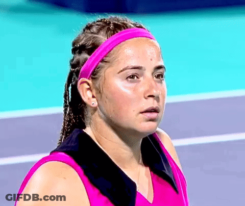 A Woman Wearing A Pink Headband And Earrings Looks At The Camera GIF